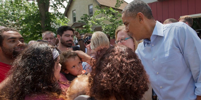 June 26, 2014: President Barack Obama greets a small child on the sidewalk outside of Matt's Bar in Minneapolis.