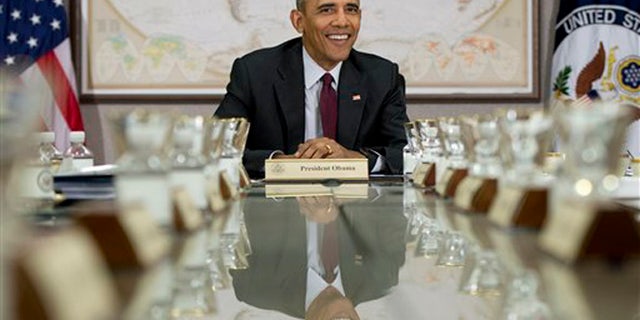 President Barack Obama is reflected in the conference table before a meeting of his National Security Council (NSC) at the State Department in Washington, Thursday, Feb. 25, 2016. The meeting is to focus on the global campaign to degrade and destroy ISIL as well as Syria and other regional issues. (AP Photo/Carolyn Kaster)