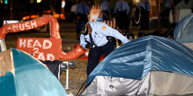 Dec. 6, 2011: A New Orleans police officer checks a tent for people as they clear out the Occupy New Orleans encampment in Duncan Plaza across from City Hall in New Orleans.