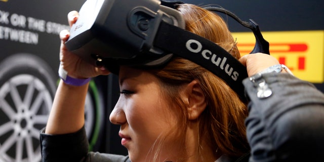 A woman puts on an Oculus virtual reality headset during preparations for the 2014 LA Auto Show in Los Angeles, California November 18, 2014. REUTERS/Lucy Nicholson