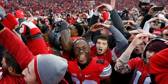FILE - In this Saturday, Nov. 26, 2016, file photo, Ohio State players and fans celebrate their win over Michigan in an NCAA college football game in Columbus, Ohio.