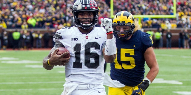 Ohio State quarterback J.T. Barrett (16) scores a touchdown, defended by Michigan defensive lineman Chase Winovich (15), in the second quarter of an NCAA college football game in Ann Arbor, Mich., Saturday, Nov. 25, 2017.