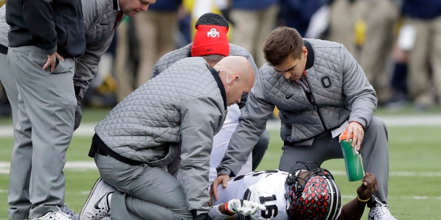 Ohio State quarterback J.T. Barrett (16) is looked at by team officials after being sacked during the second half of an NCAA college football game, Saturday, Nov. 25, 2017, in Ann Arbor, Mich.