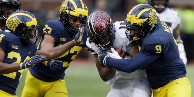 Ohio State quarterback J.T. Barrett (16) is stopped by Michigan linebacker Mike McCray (9) during the first half of an NCAA college football game, Saturday, Nov. 25, 2017, in Ann Arbor, Mich.