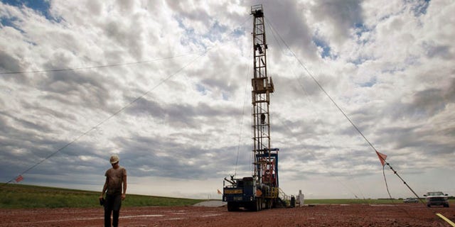 July 26, 2011: A worker walks by an oil derrick outside of Williston, N.D. Relief could be on the horizon for strapped public services in the Northern Plains' booming oil patch, as elected leaders in Montana and North Dakota move to steer more money into the region during the states' upcoming legislative sessions.
