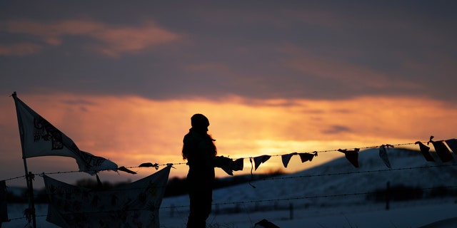 A woman watches the sunset at the Oceti Sakowin camp where people have gathered to protest the Dakota Access oil pipeline in Cannon Ball, N.D., Friday, Dec. 2, 2016.