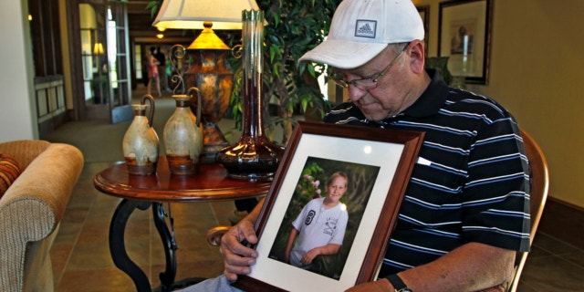May 22, 2013: Marvin Dixon, the grandfather of 8-year-old tornado victim Kyle Davis, glances down at a photo of his grandson while sitting for a portrait in the lobby of a funeral home where his grandson awaits burial, in Oklahoma City.
