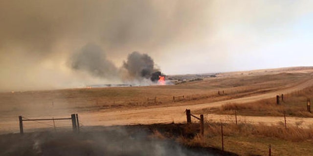 This April 5, 2016 photo provided by Landon Cates, volunteer firefighters from the Dewey County Task Force work a blaze southwest of Freedom, Okla. Oklahoma Forestry Services Director George Geissler says arcing power lines are to blame for the blaze in northwest Oklahoma, located about 170 miles northwest of Oklahoma City. (Landon Cates/Leedy Fire Department via AP)