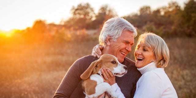 An older boomer couple enjoy time with their dog.