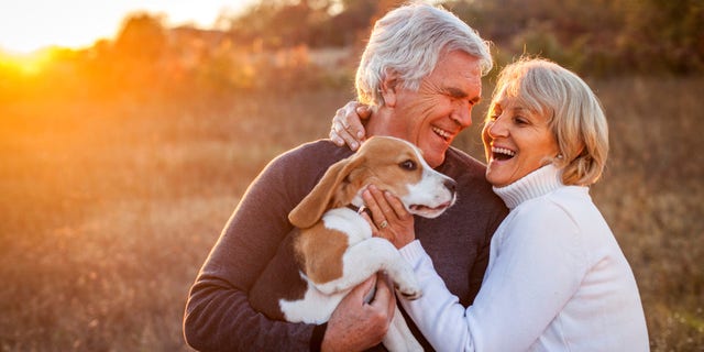 An older boomer couple enjoy time with their dog.