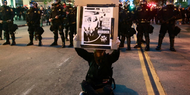 July 8: A demonstrator holds a sign in front of a moving police line in Oakland, Calif., after a guilty verdict for Johannes Mehserle. The former San Francisco Bay Area Rapid Transit police officer was found guilty in Los Angeles for shooting unarmed black man Oscar Grant on New Year's Day 2009 at a BART station in Oakland.