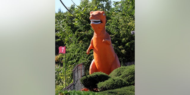 In this Monday, Sept. 12, 2016 photo, a 20-foot-high orange dinosaur stands near Route 1 in Saugus, Mass. Some feared the 20-foot dinosaur would disappear because the miniature golf course on which it has stood since 1958 was sold to a developer.