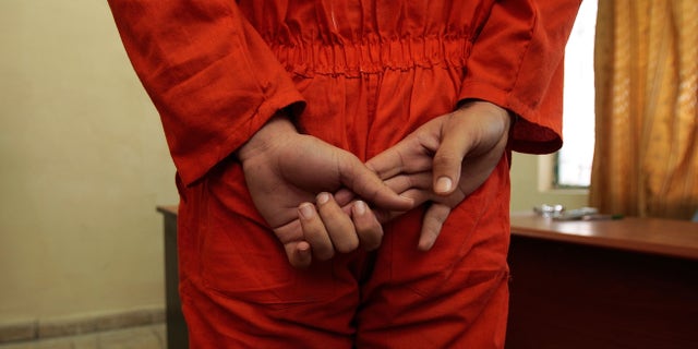 BAGHDAD, IRAQ - NOVEMBER 06: An arrested Iraqi man stands before Iraqi judges in a makeshift courtroom November 6, 2007 in Baghdad, Iraq. Around 300 Iraqi men who have been swept up in raids by Iraqi and US forces--often on charges of insurgent activity or organized crime such as kidnapping rings--are detained at a sparse rudimentary jail on a combined US-Iraqi military base here, and about five to ten a day are outfitted in orange jumpsuits and brought before a panel of judges at a nearby makeshift courtroom. Judges look over each men's file of evidence, hear the accused's statement, and route the case accordingly. Defendents are represented by an Iraqi woman lawyer, the Iraqi equivalent of a public defender. (Photo by Chris Hondros/Getty Images)