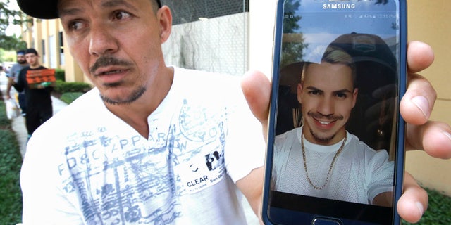 Angel Mendez, standing outside the Orlando Regional Medical Center, holds up a cell phone photo trying to get information about his brother Jean C. Mendez that was at the Pulse Nightclub where a shooting involving multiple fatalities occurred, Sunday, June 12, 2016, in Orlando, Fla. (AP Photo/John Raoux)