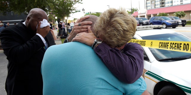 Terry DeCarlo, executive director of the LGBT Center of Central Florida, center, is comforted by Orlando City Commissioner Patty Sheehan, right, after the mass shooting at a nightclub in Orlando, Fla., on June 12, 2016.