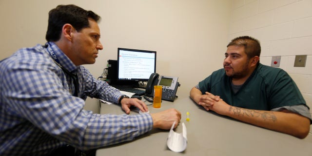 In this Tuesday, March 1, 2016, photograph, Dr. Josh Blum, left, confers with inmate Lee Gonzales at the Denver County Jail in downtown Denver. Jails and correction agencies across the country such as Denver are teaching soon-to-be-released inmates how to use the heroin overdose antidote called naloxone, either to save others and sometimes themselves. (AP Photo/David Zalubowski)