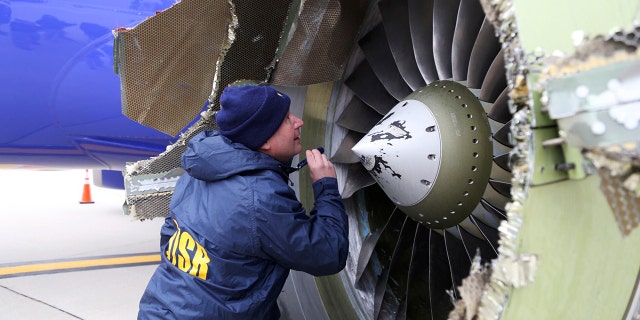 A National Transportation Safety Board investigator examines damage to the engine of the Southwest Airlines plane that made an emergency landing at Philadelphia International Airport.