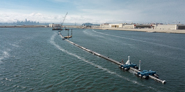 In this Monday, Aug. 27, 2018 photo provided by The Ocean Cleanup, a long floating boom that will be used to corral plastic litter in the Pacific Ocean is assembled in Alameda, Calif. Engineers will deploy a trash collection device to corral plastic litter floating between California and Hawaii in an attempt to clean up the world's largest garbage patch. The 2,000-foot long floating boom will be towed Saturday, Sept. 8, 2018, from San Francisco to the Great Pacific Garbage Patch, an island of trash twice the size of Texas.
