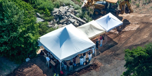 Investigators gather under tents as they search a property, Wednesday, July 12, 2017, in Solebury, Pa.