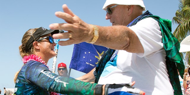 Victoria Burgess, left, reaches to embrace her father, Arthur Burgess, right, on Wednesday in Key West, Fla. after she standup paddleboarded from Cuba to the southernmost city in the continental U.S.