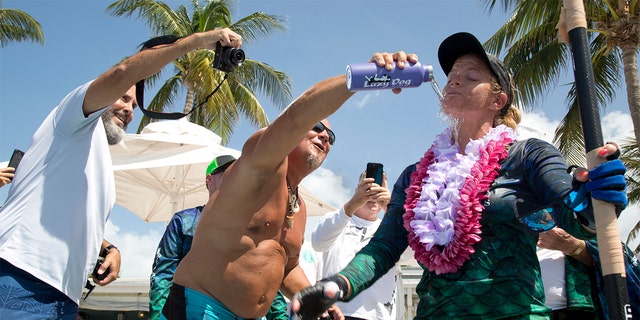 Jeff Keine, center, douses Victoria Burgess, right, with water after she completed her journey from Cuba to Key West, Fla.