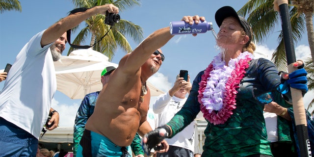 Jeff Keine, center, douses Victoria Burgess, right, with water after she completed her journey from Cuba to Key West, Fla.