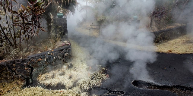 Steam and sulfur rises from cracks in Moku Street at the head of a driveway in Leilani Estates, Tuesday, May 8, 2018, in Pahoa, Hawaii.