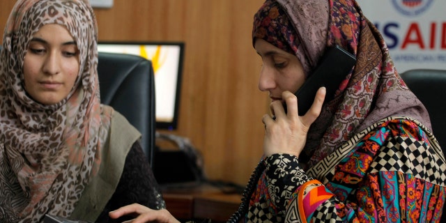 Pakistani lawyer Shandana Naeem, right, listens to a caller to a domestic violence helpline with her colleague Nayab Hassan at their office in Peshawar, Pakistan, on March 28, 2017.