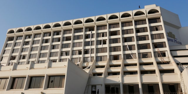 A rescue worker stands on the floor as broken windows are seen with bed sheets used by guests to escape a fire erupted in a hotel early morning in Karachi, Pakistan, December 5, 2016.