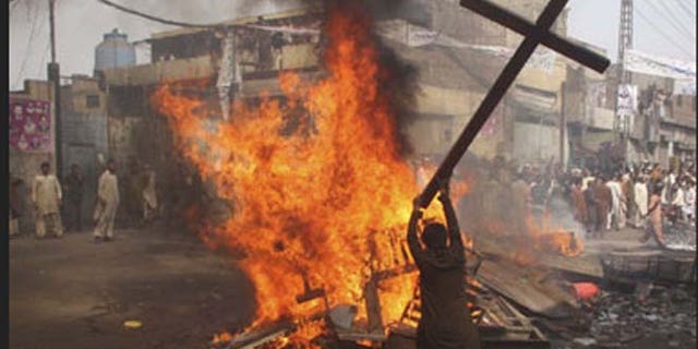 Pakistani man is shown burning a cross.