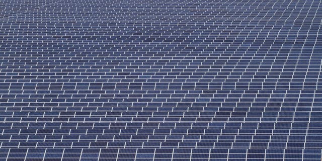 Indian workers walk past solar panels at the Gujarat Solar Park in India.