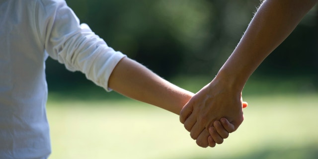 A mother holds his child's hand