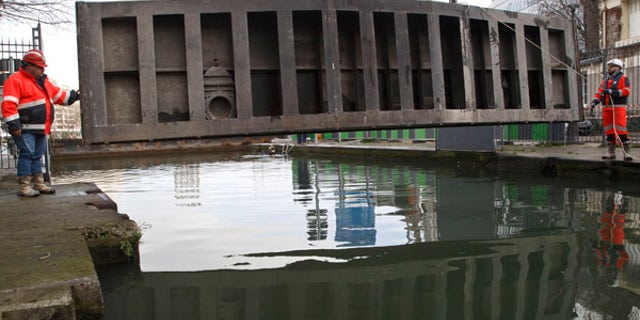 Jan. 4, 2016: Municipal workers guide a lock plate at the Canal-Saint Martin, as it is drained for maintenance in Paris (AP)