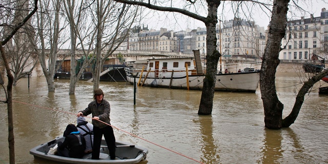 People use a dinghy boat to reach a barge on the river Seine in Paris, Saturday, Jan. 27, 2018.