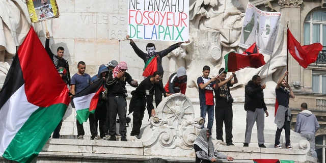 July 13, 2014: Pro-Palestinian demonstrators wave Palestinian flags and chant anti Israeli slogans on the statue of Republic in Paris, to protest against the Israeli army's bombings in the Gaza strip. Banner reads: "Netanyahu gravedigger of peace." About 10,000 pro-Palestinian protesters marched through eastern Paris on Sunday demanding an end to Israeli strikes on Gaza, and accusing Western leaders of not doing enough to stop them.