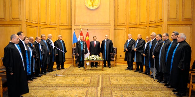 In this image released by the Egyptian President, Egyptian President Mohammed Morsi, center left, stands with judges Farouk Sultan, second left, and Maher el-Beheri, center right, as he is sworn in at the Supreme Constitutional Court in Cairo, Egypt, Saturday, June 30, 2012. Islamist Mohammed Morsi promised a "new Egypt" and unwavering support to the powerful military as he took the oath of office Saturday to become the country's first freely elected president, succeeding Hosni Mubarak who was ousted 16 months ago. (AP Photo/Egyptian Presidency)