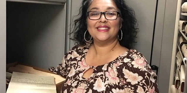 In this photo provided by the Doña Ana County Manager's Office, Records and Filing Supervisor Angelica Valenzuela poses at the Doña Ana County Clerk's Office Friday, May 19, 2017, in Las Cruces, N.M. Valenzuela found a century-old document inside a box of unarchived records that sheds light on the death of the Old West lawman Pat Garrett who gained fame for killing Billy the Kid. (Doña Ana County Manager's Office via AP)