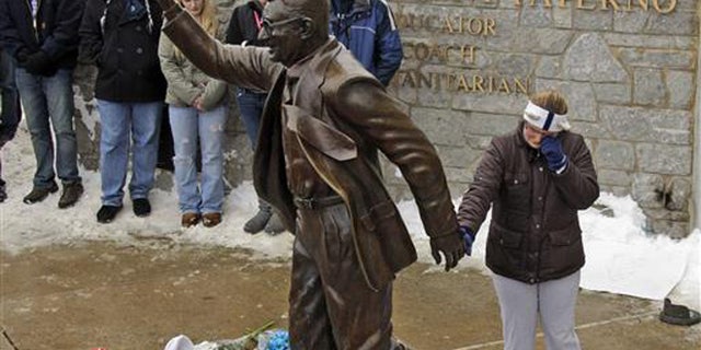 In this Jan. 22, 2012, file photo, a woman pays her respects at a statue of former Penn State football coach Joe Paterno outside Beaver Stadium on the Penn State University campus in State College, Pa.