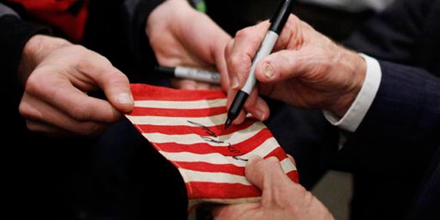 Dec. 29, 2011: Ron Paul signs a flag for a supporter as he campaigns in Council Bluffs, Iowa.