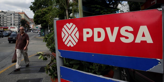A man walks past the corporate logo of the state oil company PDVSA at a gas station in Caracas, Venezuela December 1, 2017. REUTERS/Marco Bello - RC1F873E1C20