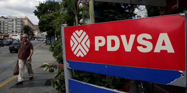A man walks past the corporate logo of the state oil company PDVSA at a gas station in Caracas, Venezuela December 1, 2017. REUTERS/Marco Bello - RC1F873E1C20
