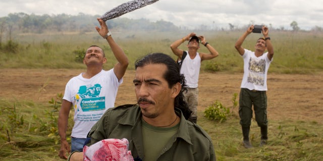 Rebels wave as a helicopter transporting FARC leaders takes off from Yari Plains, Colombia, Sept. 24, 2016.
