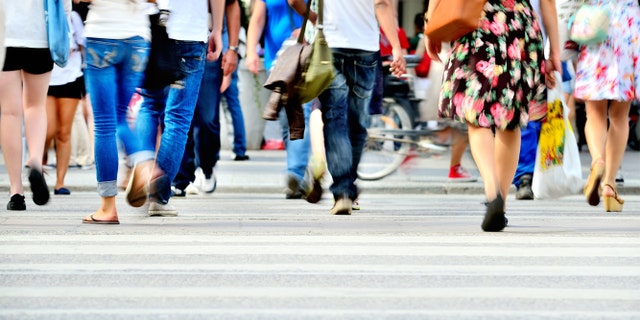 Motion blurred pedestrians crossing sunlit street