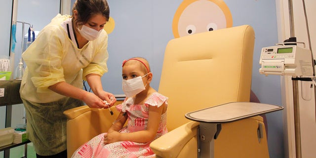 Alexandra Munoz, 5, who lost her hair due to chemotherapy to treat a malignant brain tumor, undergoes a session of treatment with the help of a nurse in the cancer ward of the Luis Calvo Mackenna Hospital in Santiago, October 20, 2014. REUTERS/Rodrigo Garrido