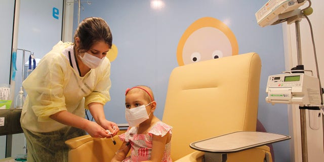 Alexandra Munoz, 5, who lost her hair due to chemotherapy to treat a malignant brain tumor, undergoes a session of treatment with the help of a nurse in the cancer ward of the Luis Calvo Mackenna Hospital in Santiago, October 20, 2014. REUTERS/Rodrigo Garrido