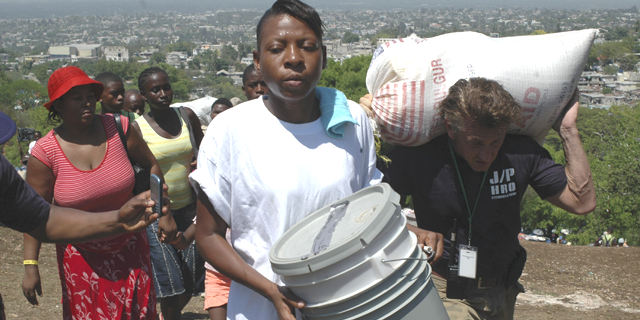 Sean Penn (R) helps to carry the belongings of a earthquake victims during a relocation exercise in Port-au-Prince April 10, 2010. (Reuters)