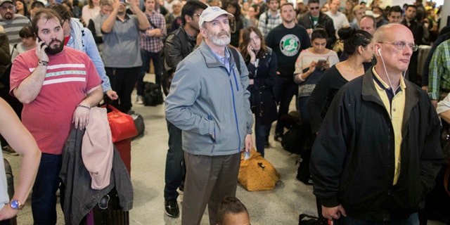 Evening rush hour commuters look at the departures board while at Penn Station, Friday, April 14, 2017, in New York. A New Jersey Transit train with about 1,200 passengers aboard is stuck in a Hudson River tunnel between New York and New Jersey. Authorities say the Northeast Corridor train became disabled Friday due to an Amtrak overhead power problem. (AP Photo/Mary Altaffer)