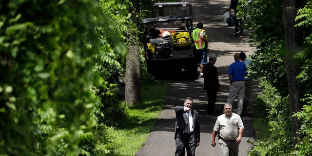 Law enforcement officials walk down a blocked off drive way, Monday, July 10, 2017, in Solebury, Pa.