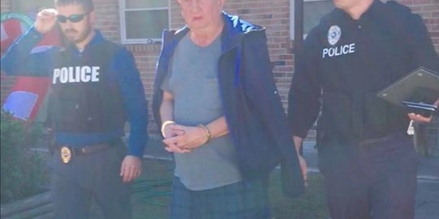 Michael Neu, shown being taken into custody, faces 269 counts of wire fraud and one count of money laundering, authorities say.