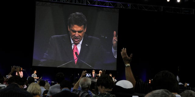 Worshippers pray with Texas Gov. Rick Perry, seen at center and on screen, at The Response, a day long prayer and fast rally, Saturday, Aug. 6, 2011, at Reliant Stadium in Houston.